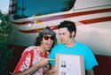 Nardwuar pointing to a picture of Senator Mike Burkett (D-ID) Idaho , besides another guy called Mike Burkett: Fat Mike! Warped Tour 2004, Vancouver, BC, Canaduh!