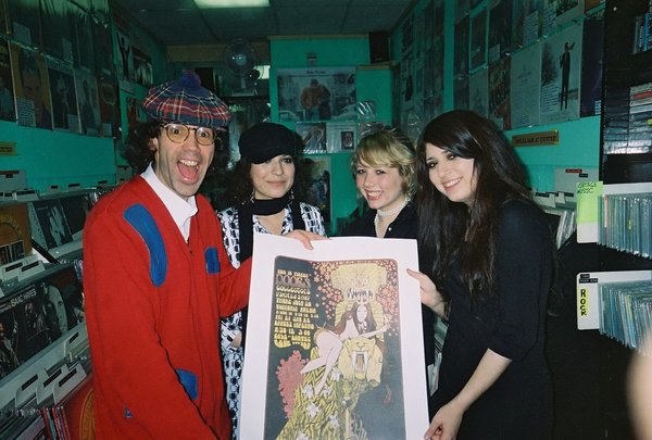The Magenta Lane and Nardwuar inside of "Noize to Go" Records, Vancouver, BC.  (Holding a poster that features Vancouver's 60s garage punk legends The Painted Ship backing up the Doors)